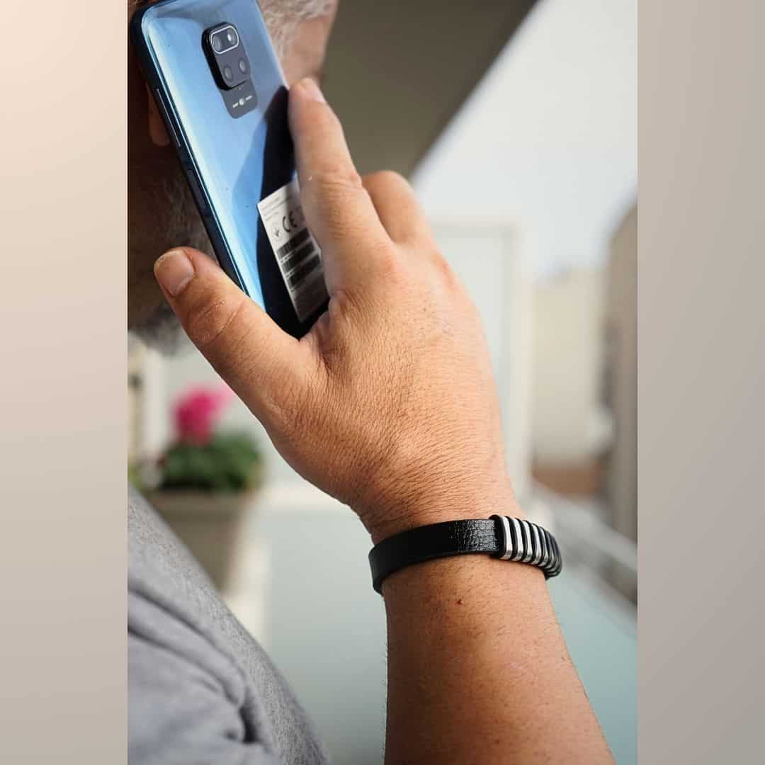 Pulsera de acero y cuero en mano de hombre que habla por teléfono